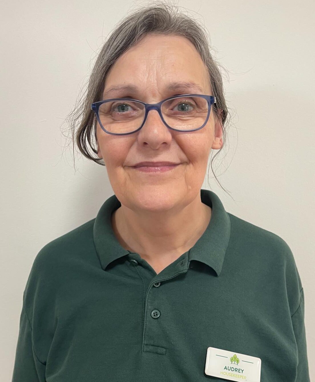 woman with glasses wearing a dark green polo shirt