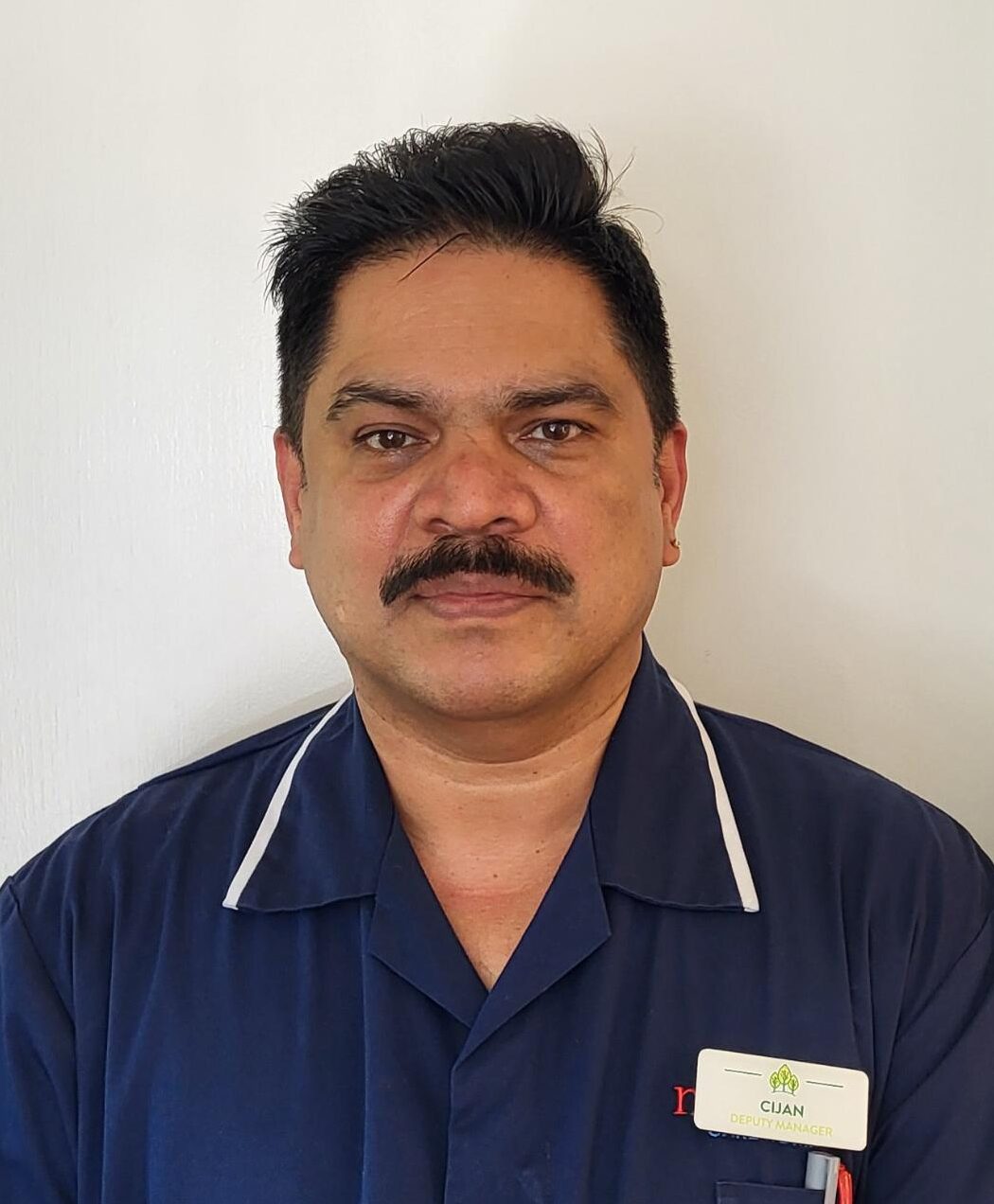 man with dark hair and moustache wearing a dark blue nurses uniform
