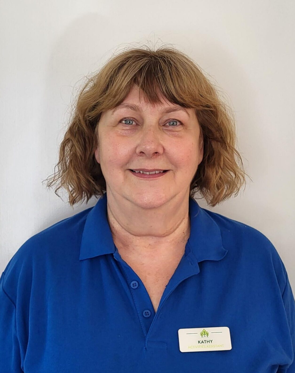 woman with blonde bob smiling in dark blue polo shirt