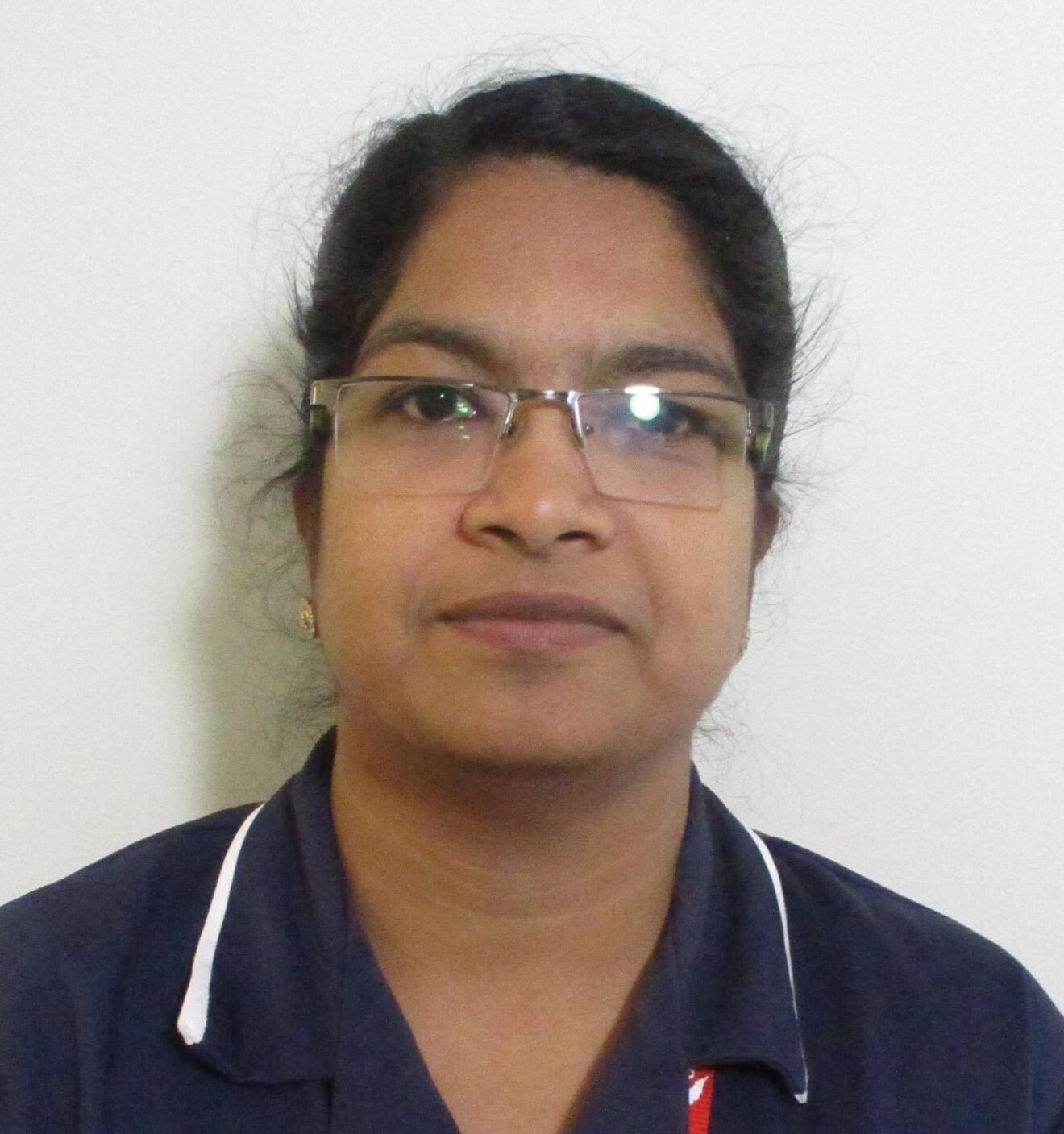 woman with glasses wearing a dark blue nurses uniform