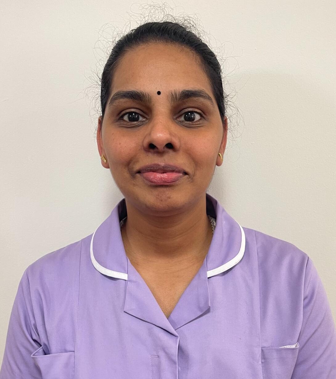 woman with hair tied back in lavender nurses uniform