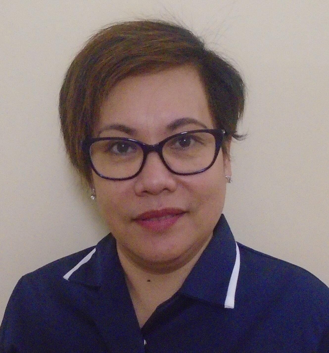 woman with short hair and glasses in a dark blue nurses uniform